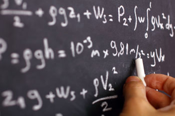 Ein Physiker schreibt viele Formeln an eine Tafel