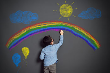 Junge malt Regenbogen und Sonne auf Tafel