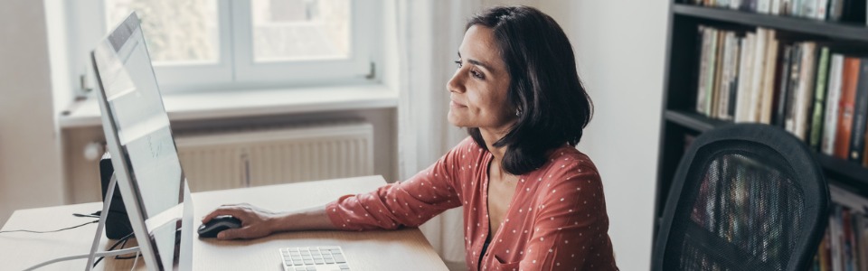 Fernstudierende Frau lernt am Schreibtisch am PC.