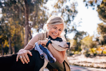 Tierheilpraktikerin ist mit ihrem Hund im Freien und umarmt ihn.