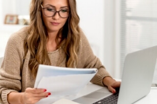 Eine Studentin sitzt an ihrem Laptop, hört Musik und lernt dabei