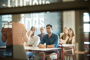 MBA berufsbegleitend: Berufstätige sitzen im Seminar und hören der Dozentin zu.