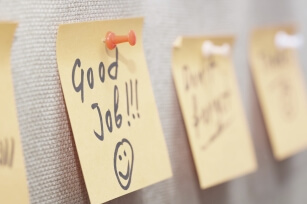 Ein paar Zettel sind auf einem Korkbrett aufgepinnt, auf einem ist "Good Job" zu erkennen