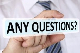 Ein Student hält ein fiktives Schild zwischen Daumen und Zeigefinger, auf dem "Any Questions?" steht