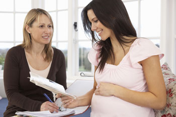 Hebamme und schwangere Frau sitzen beim Gespräch zusammen
