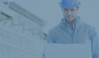 Ein Architekt mit Schutzhelm und Bauplan vor einem Gebäude.