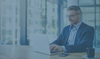 Ein Mann sitzt am Schreibtisch und arbeitet an einem Laptop.