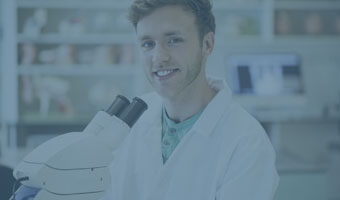 Ein Chemiker in weißem Kittel mit einem Mikroskop im Labor.