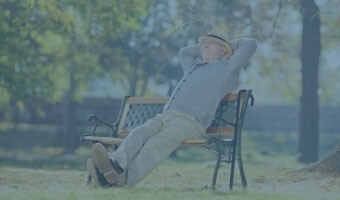 Ein alter Mann sitzt auf einer Parkbank.