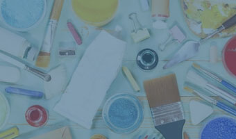 Vogelperspektive auf verschiedene Mal-Utensilien wie Pinsel, Spachtel, Farbe und Tinte. 