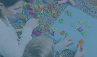 Eine Logopädin arbeitet mit einem Kind mit Hilfe von Buchstaben-Formen.