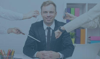 Ein lächelnder Mann im Anzug sitzt am Schreibtisch während ihm vier Arme aus den Seiten des Bildes Uhr, Handy und Tablet entgegenstrecken.