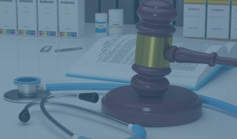 Auf einem Tisch liegen ein Richterhammer, Stetoskop, Pillendosen und Lehrbücher.