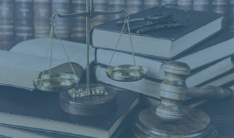 Auf einem Schreibtisch liegen Bücher, ein Richterhammer, ein Schlüssel und die Waage der Justitia.