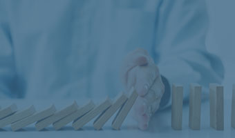 Ein Mann verhindert die Kettenreaktion einer Reihe Dominosteine.